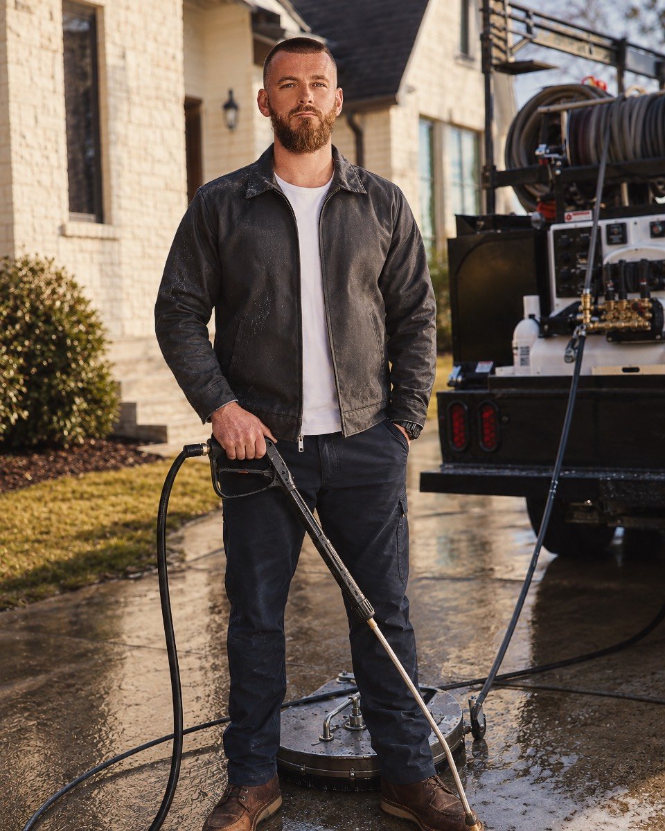 Owner of Surge Wash Co. standing beside the pressure-washing rig